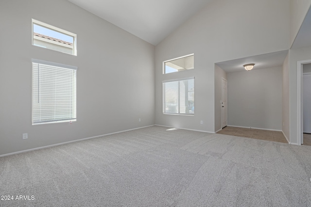 carpeted empty room featuring a healthy amount of sunlight and high vaulted ceiling