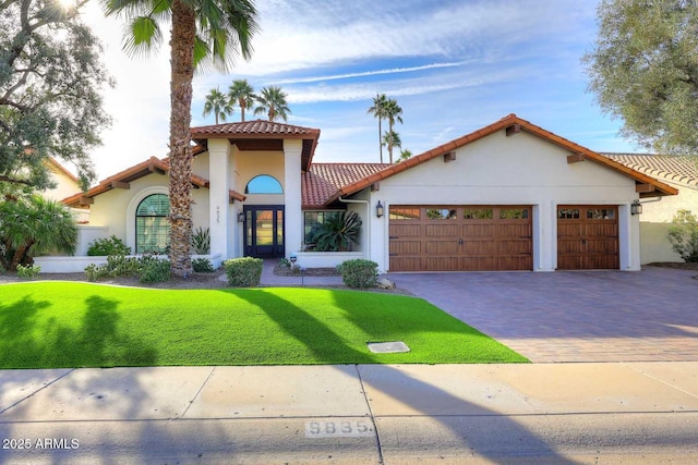 mediterranean / spanish-style home with a garage and a front lawn