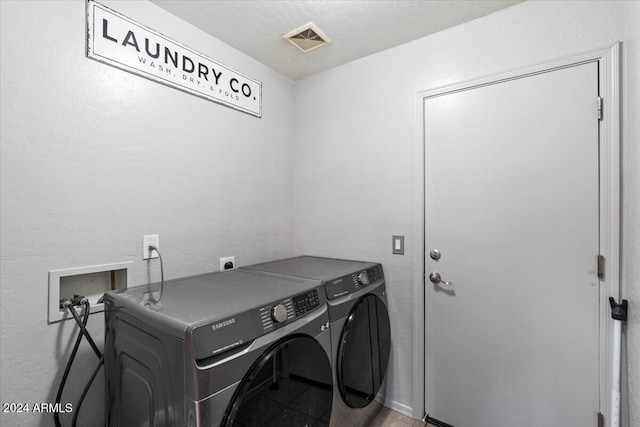 washroom with a textured ceiling and separate washer and dryer