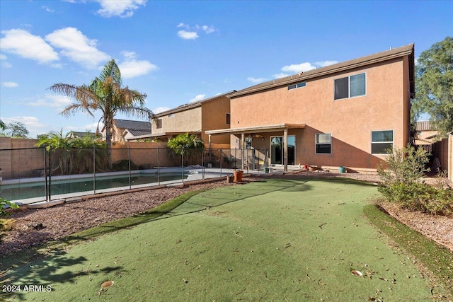 back of property with a patio area and a fenced in pool