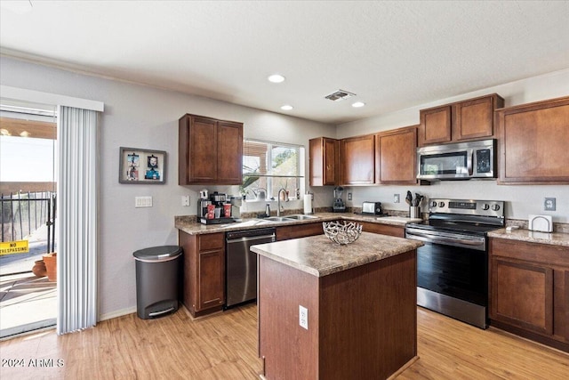 kitchen featuring sink, stainless steel appliances, a center island, and light wood-type flooring