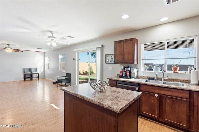 kitchen featuring sink, light wood-type flooring, a kitchen island, dishwasher, and ceiling fan