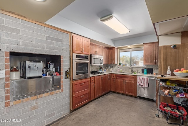 kitchen featuring appliances with stainless steel finishes, brown cabinets, light countertops, and concrete floors