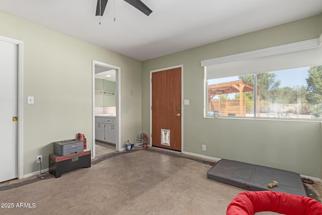 interior space with concrete flooring, baseboards, and a ceiling fan