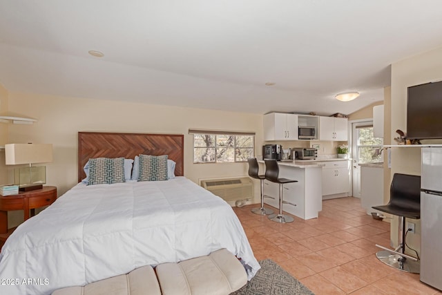 bedroom featuring a toaster, light tile patterned floors, freestanding refrigerator, vaulted ceiling, and a wall mounted air conditioner