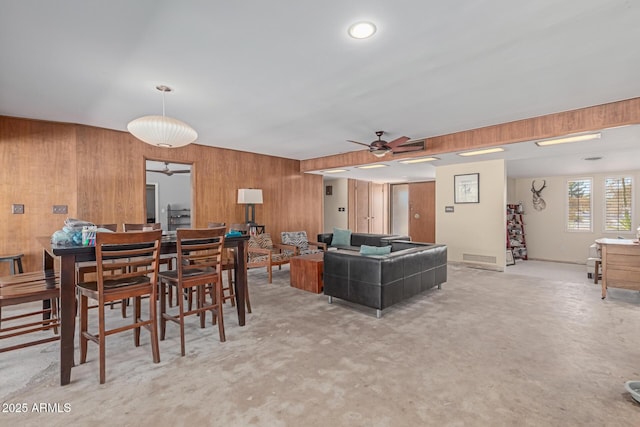 living room featuring wood walls and ceiling fan