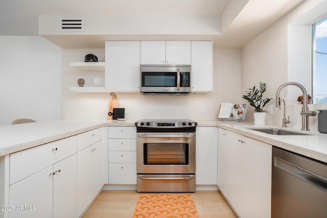 kitchen featuring stainless steel appliances, light hardwood / wood-style flooring, white cabinetry, and sink