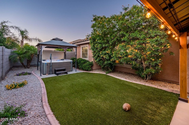 2678 S 172nd Dr, Goodyear, AZ 85338 - yard at dusk with a hot tub, a gazebo, and a patio area