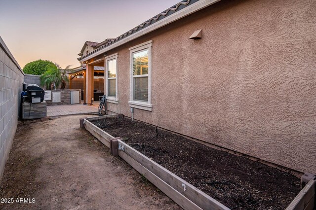2678 S 172nd Dr, Goodyear, AZ 85338 - view of side of home featuring stucco siding, a garden, a fenced backyard, a patio, and a tile roof