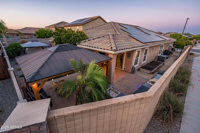 2678 S 172nd Dr, Goodyear, AZ 85338 - back of property at dusk featuring roof mounted solar panels, a fenced backyard, and a gazebo