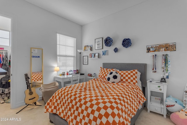 bedroom with a walk in closet, a closet, light colored carpet, and multiple windows