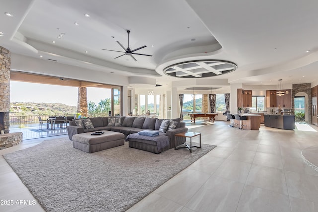 living area featuring a ceiling fan, a tray ceiling, plenty of natural light, and recessed lighting