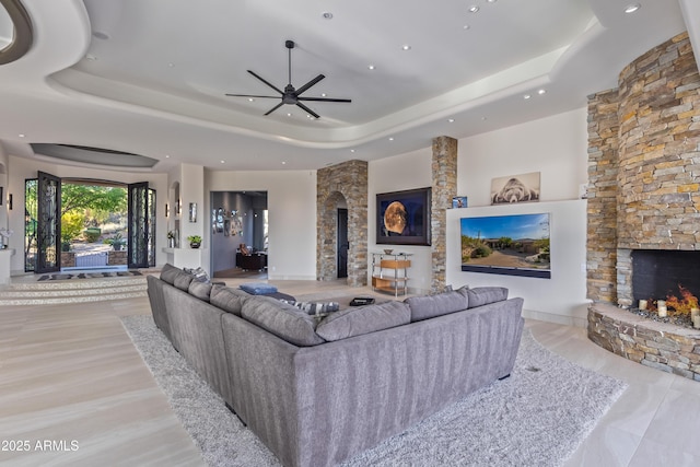 living room with ceiling fan, a fireplace, a raised ceiling, and recessed lighting