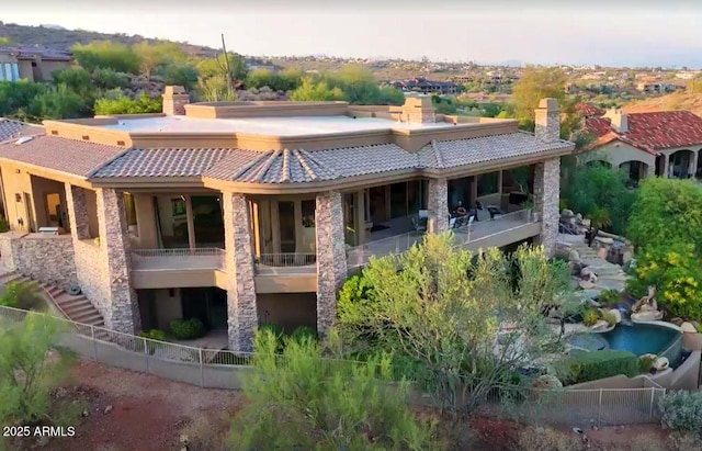 back of property featuring a tile roof, fence, a chimney, and stucco siding