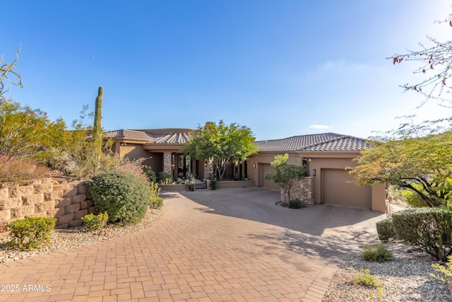 view of front of property featuring a garage, a tiled roof, decorative driveway, and stucco siding