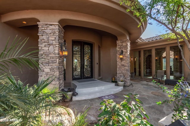 property entrance with stone siding, french doors, and stucco siding