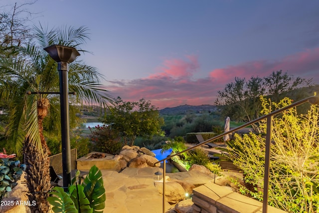 patio terrace at dusk with an outdoor fire pit and a water view