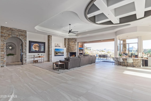 living room featuring ceiling fan, a high ceiling, and a fireplace