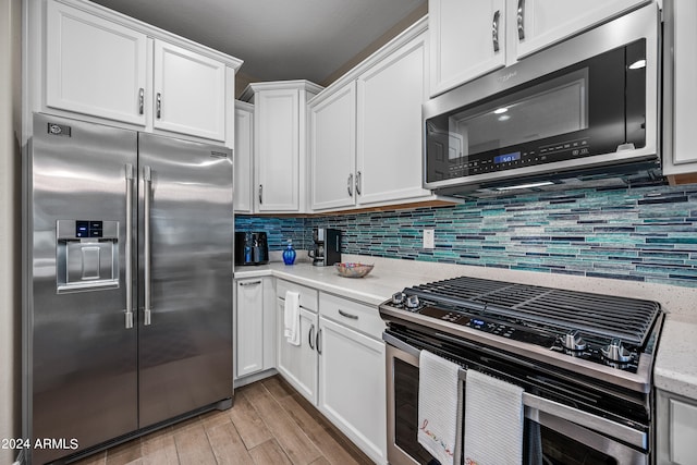 kitchen featuring tasteful backsplash, white cabinetry, stainless steel appliances, light stone countertops, and light wood-type flooring