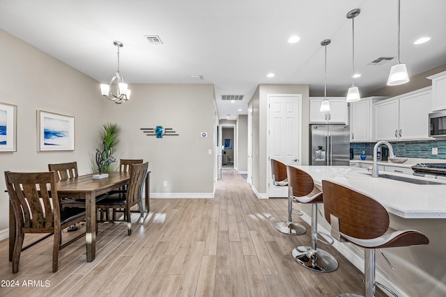 kitchen featuring a kitchen bar, sink, appliances with stainless steel finishes, pendant lighting, and white cabinets