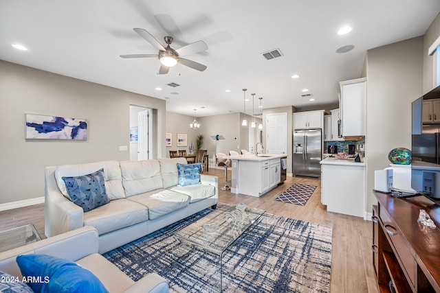 living room featuring ceiling fan, sink, and light hardwood / wood-style flooring