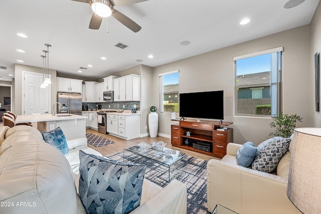 living room with ceiling fan, sink, and light hardwood / wood-style floors