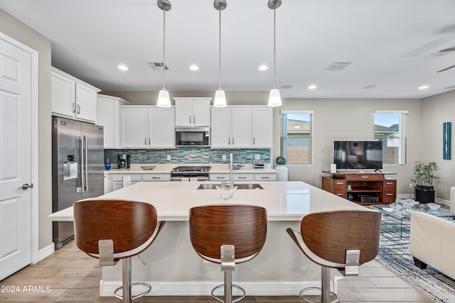 kitchen with stainless steel appliances, sink, pendant lighting, and white cabinets