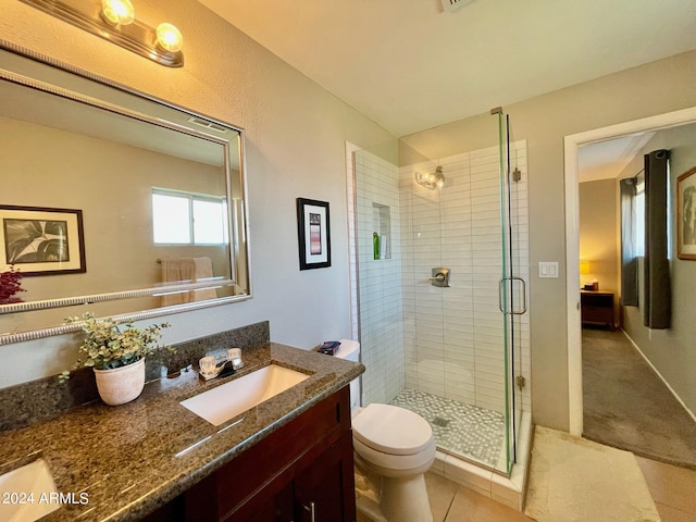 bathroom with a shower with door, vanity, tile patterned floors, and toilet