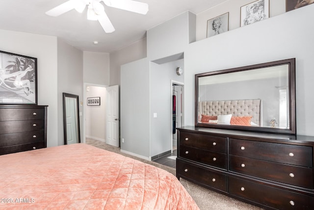 carpeted bedroom featuring a spacious closet, a closet, a ceiling fan, and baseboards