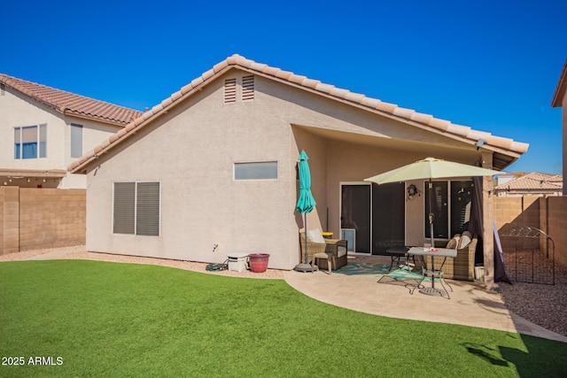 back of house with a yard, a fenced backyard, a patio, and stucco siding