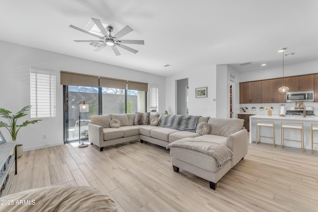 living room featuring ceiling fan and light hardwood / wood-style flooring