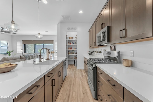 kitchen with decorative light fixtures, sink, light hardwood / wood-style flooring, and stainless steel appliances