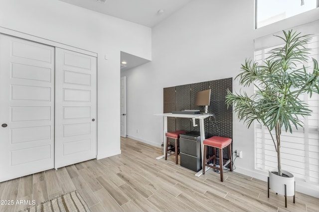 office featuring a towering ceiling and light hardwood / wood-style flooring