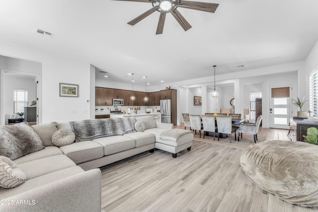 living room featuring light hardwood / wood-style flooring and ceiling fan