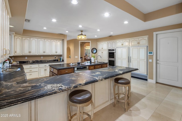 11809 S Montezuma Ct, Phoenix, AZ 85044 - kitchen featuring a sink, a breakfast bar area, stainless steel double oven, light tile patterned floors, and arched walkways