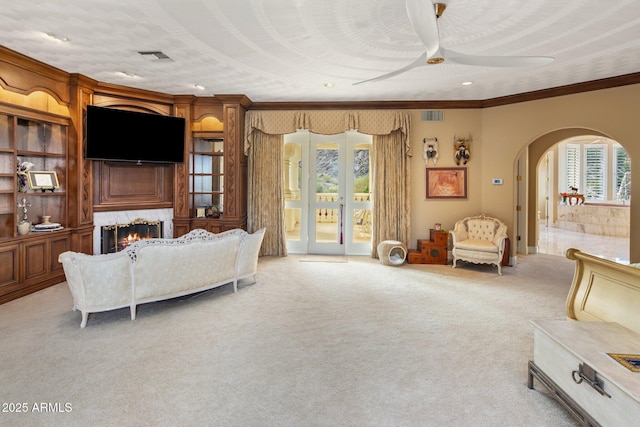 11809 S Montezuma Ct, Phoenix, AZ 85044 - living area with arched walkways, a lit fireplace, light carpet, ceiling fan, and crown molding