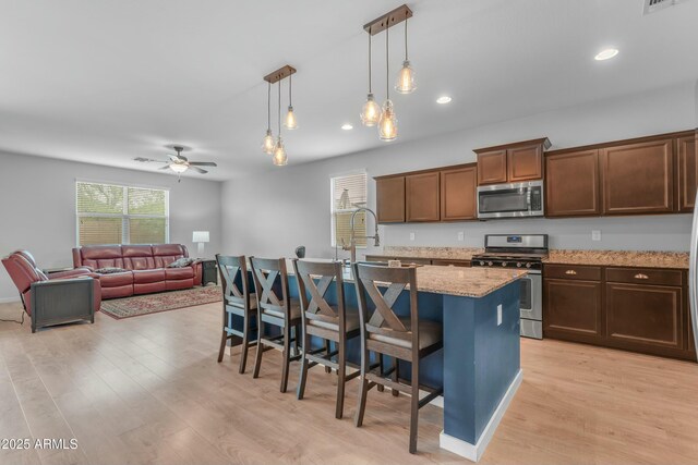 696 W Glen Canyon Dr, San Tan Valley, AZ 85140 - kitchen featuring a kitchen island with sink, stainless steel appliances, a breakfast bar area, and light wood finished floors
