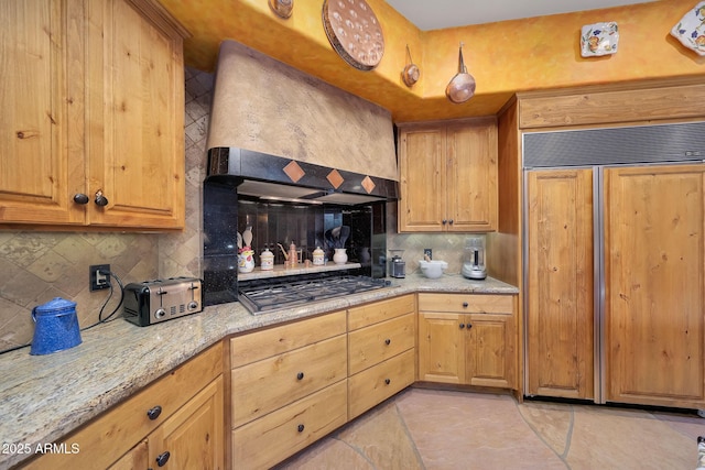 kitchen with stainless steel gas stovetop, paneled built in refrigerator, custom range hood, and tasteful backsplash