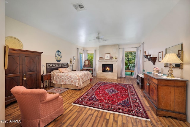 bedroom with hardwood / wood-style floors, ceiling fan, and a fireplace