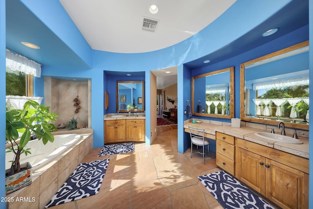 bathroom featuring tiled tub, tile patterned flooring, and vanity