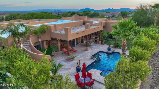 pool at dusk featuring a fireplace and a patio