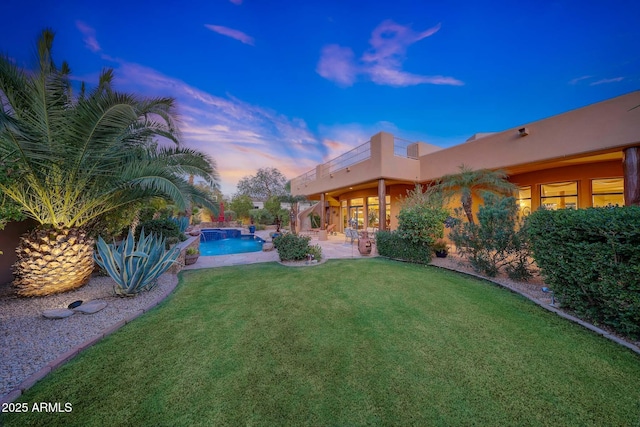 yard at dusk featuring a patio area and a balcony