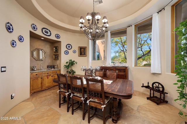 dining area with a tray ceiling and a notable chandelier