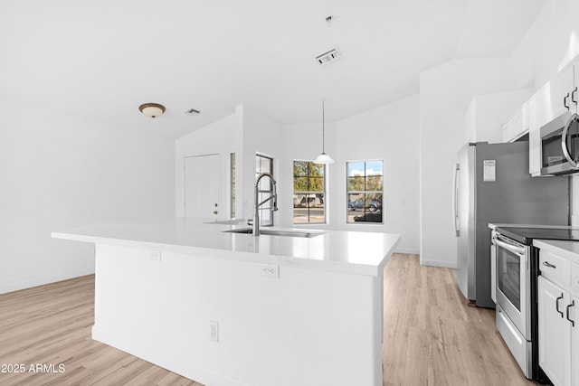 kitchen featuring a center island with sink, visible vents, appliances with stainless steel finishes, hanging light fixtures, and light countertops