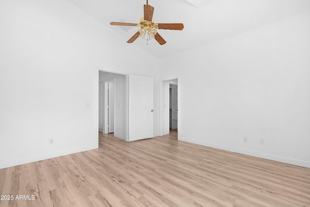 empty room with high vaulted ceiling, light wood finished floors, a ceiling fan, and baseboards