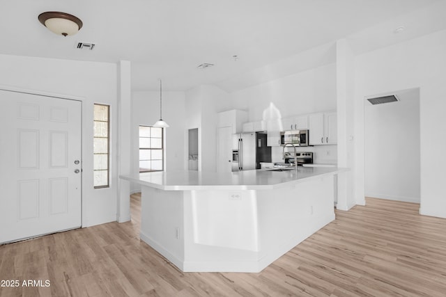 kitchen featuring visible vents, white cabinetry, light countertops, appliances with stainless steel finishes, and a large island