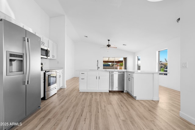 kitchen featuring a peninsula, a sink, white cabinetry, light countertops, and appliances with stainless steel finishes