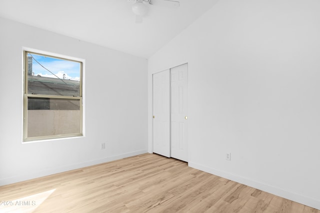 spare room featuring light wood-style floors, vaulted ceiling, baseboards, and ceiling fan