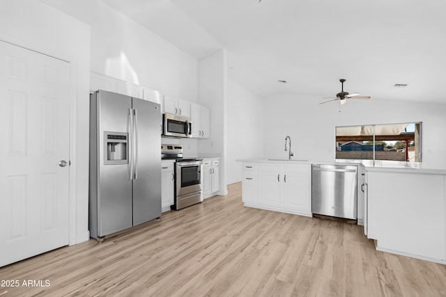 kitchen featuring white cabinets, stainless steel appliances, light countertops, light wood-style floors, and a sink