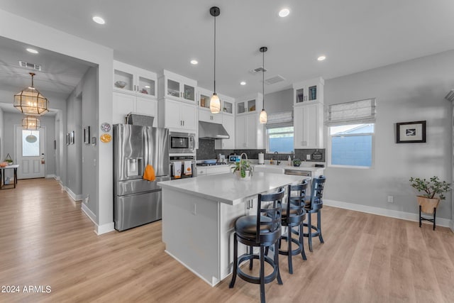 kitchen with a center island, light hardwood / wood-style flooring, white cabinetry, appliances with stainless steel finishes, and decorative light fixtures